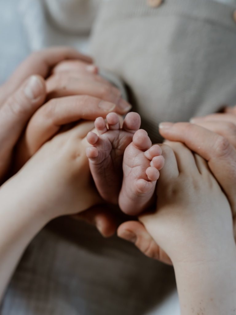 Schlafendes Baby mit sanften Händen, in hellem, weichen Licht.